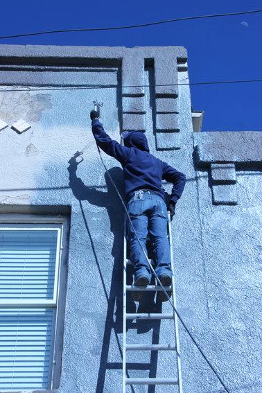 Painter David Rodriguez, whose construction skills mean he's an essential worker, applies a coat to a building downtown.